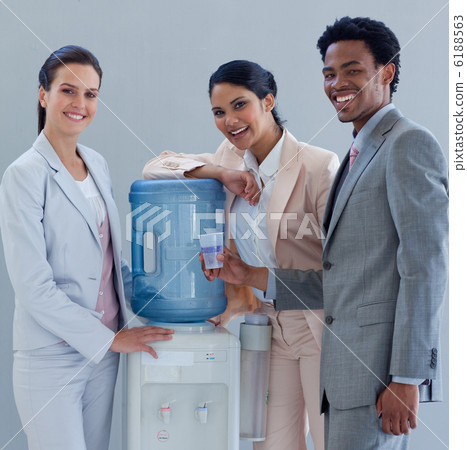 Smiling business people with a water cooler in office Smiling business people with a water cooler in office 6188563
