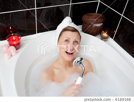 Cheerful young woman singing in a bubble bath 6189166
