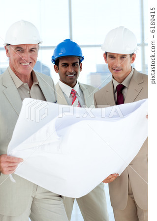 Smiling architects with hardhat looking at blueprints Smiling architects with hardhat looking at blueprints 6189415