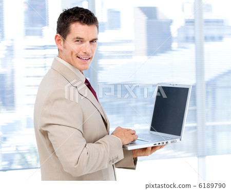 Positive businessman using a laptop standing 6189790