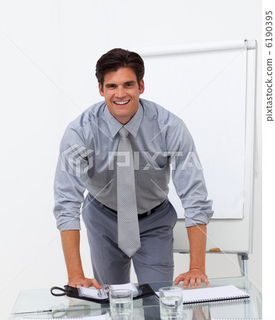 Cheerful businessman leaning on a conference table Cheerful businessman leaning on a conference table 6190395