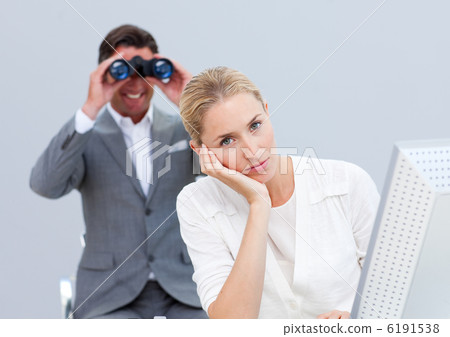 Blond businesswoman annoyed by a man looking through binoculars Blond businesswoman annoyed by a man looking through binoculars 6191538