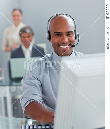 Confident businessman with headset on working at a computer Confident businessman with headset on working at a computer 6193253