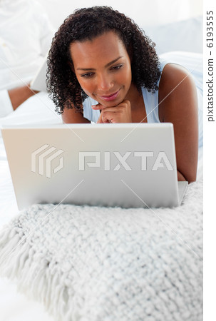Smiling woman using a laptop on her bed 6193555