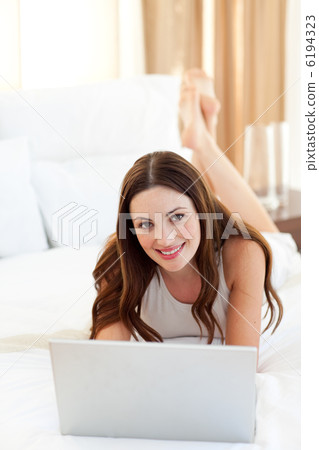 Positive woman looking at a laptop lying on bed 6194323