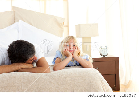 Sad little girl lying on bed with her father Sad little girl lying on bed with her father 6195087