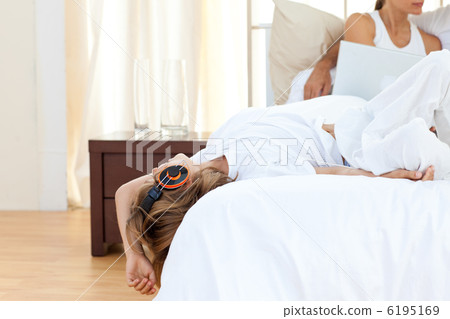 Cute boy listening music lying on bed Cute boy listening music lying on bed 6195169