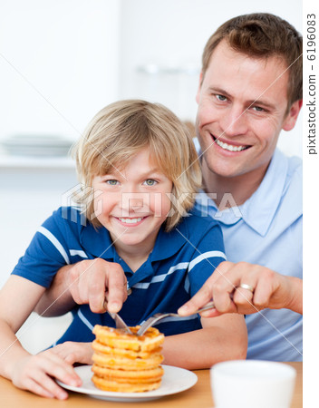 Smiling father and his son eating waffles Smiling father and his son eating waffles 6196083