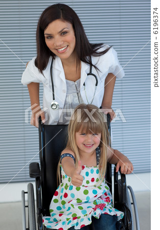 Young female doctor and Smiling girl on a wheelchair with thumb 6196374
