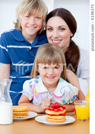 Portrait of a mother and her children having breakfast Portrait of a mother and her children having breakfast 6196375