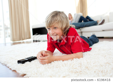 Concentrated boy watching TV lying on the floor Concentrated boy watching TV lying on the floor 6196418