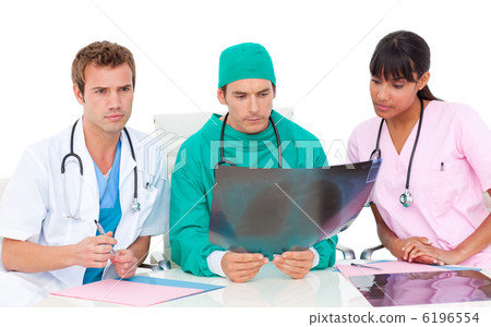 Serious medical team looking at X-ray 6196554