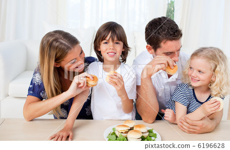 Loving family eating burgers in the living room Loving family eating burgers in the living room 6196628