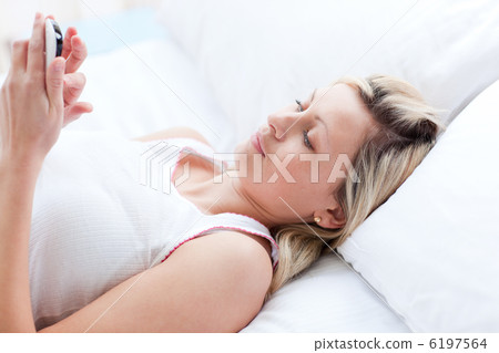 Concentrated woman sending a text lying on a bed 6197564