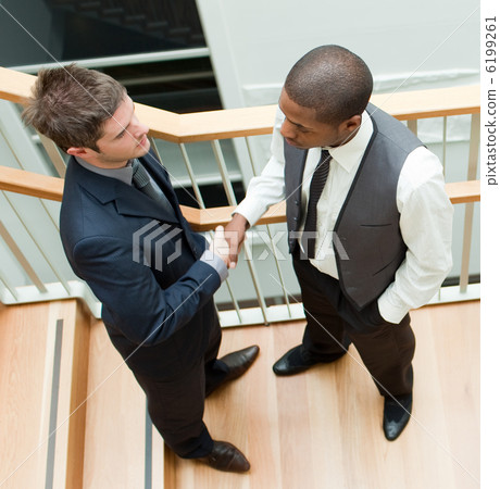 Two businessmen shaking hands on stairs 6199261