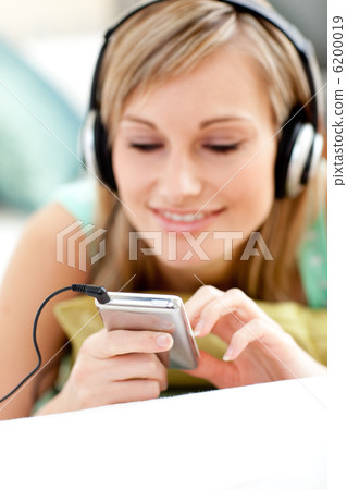 Attractive blond woman listening music lying on a sofa 6200019