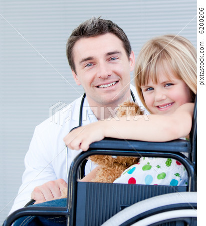 Cute little girl sitting on a wheelchair with her doctor Cute little girl sitting on a wheelchair with her doctor 6200206