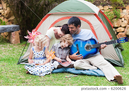Parents and children playing a guitar in a tent Parents and children playing a guitar in a tent 6200626