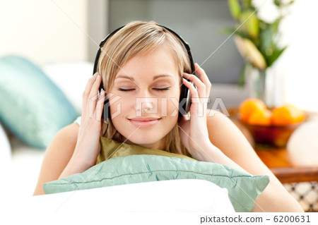 Relaxed blond woman listening music lying on a sofa Relaxed blond woman listening music lying on a sofa 6200631