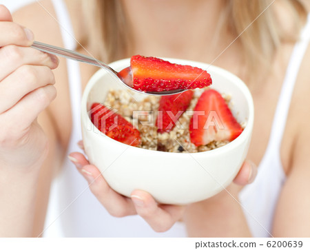 Close-up of a woman eating cereals with strawberries 6200639