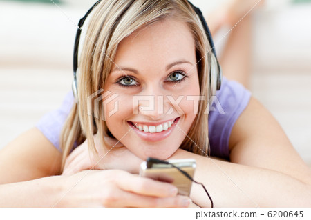 Happy woman listening music lying on the floor Happy woman listening music lying on the floor 6200645