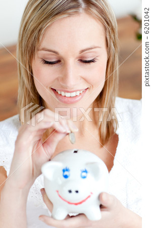 Delighted woman saving money in a piggy-bank Delighted woman saving money in a piggy-bank 6201042