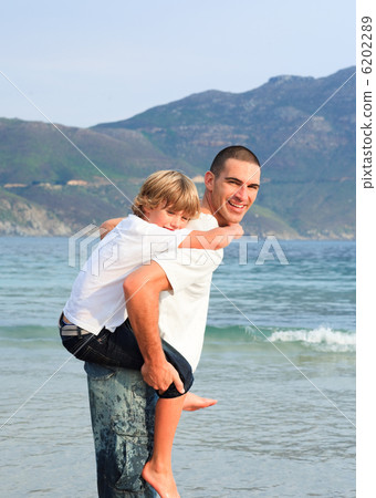Father giving his son piggyback ride on the beach Father giving his son piggyback ride on the beach 6202289