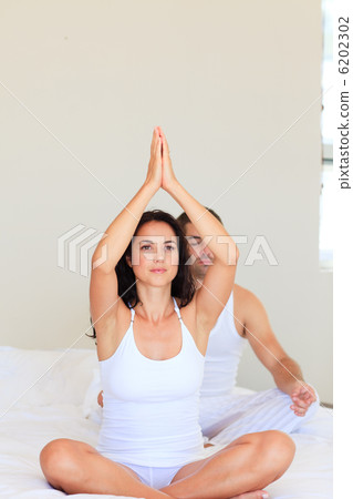 Couple practicing yoga in bed Couple practicing yoga in bed 6202302