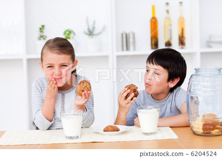 Happy Siblings eating cookies and drinking milk Happy Siblings eating cookies and drinking milk 6204524