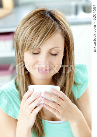 Delighted woman holding a cup of coffee in the kitchen Delighted woman holding a cup of coffee in the kitchen 6204594