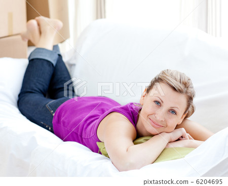 Portrait of a joyful woman relaxing on a sofa with boxes 6204695