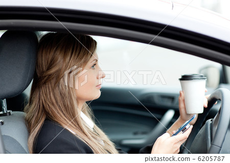 Blond businesswoman sending a text while driving 6205787