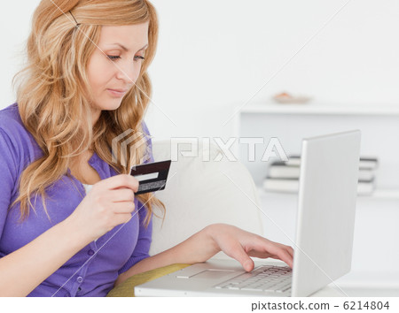 Concentrated woman sitting on a sofa is going to make a payment Concentrated woman sitting on a sofa is going to make a payment 6214804