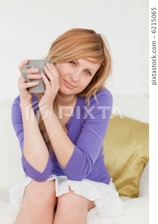 Pretty red-haired woman holding a cup of coffee and posing while Pretty red-haired woman holding a cup of coffee and posing while 6215065