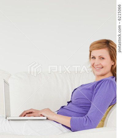 Good looking red-haired woman using a laptop and posing while ly Good looking red-haired woman using a laptop and posing while ly 6215066