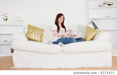 Good looking female sitting on a sofa is going to make a payment Good looking female sitting on a sofa is going to make a payment 6215415