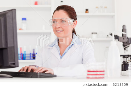 Cute scientist typing a report with her computer Cute scientist typing a report with her computer 6215509