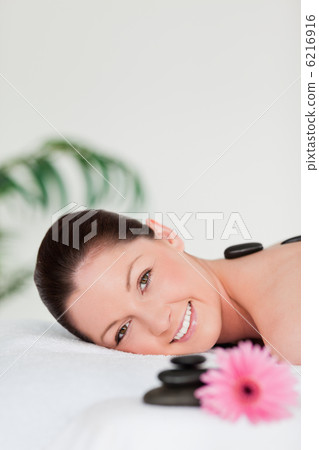 Portrait of a young woman with massage stones and a pink gerbera Portrait of a young woman with massage stones and a pink gerbera 6216916