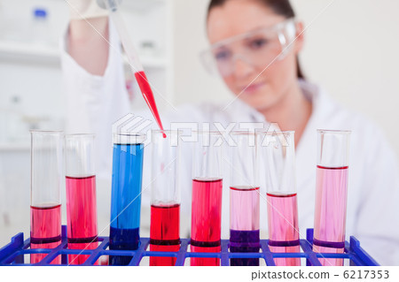 Beautiful female biologist holding a manual pipette with sample 6217353