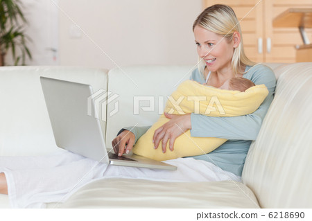 Mother with laptop on the couch holding her baby 6218690