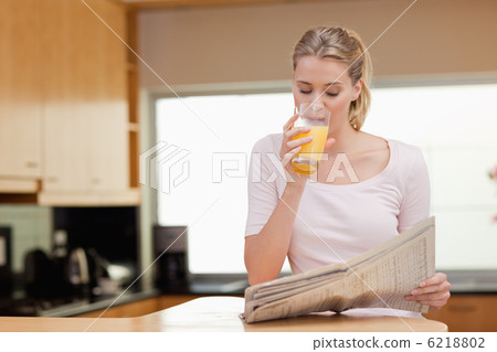 Young woman reading the news while drinking orange juice Young woman reading the news while drinking orange juice 6218802