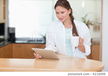 Woman using a tablet computer while drinking tea Woman using a tablet computer while drinking tea 6218898