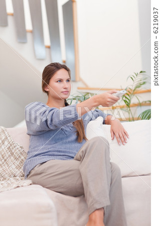 Portrait of a woman switching channel with a remote 6219037