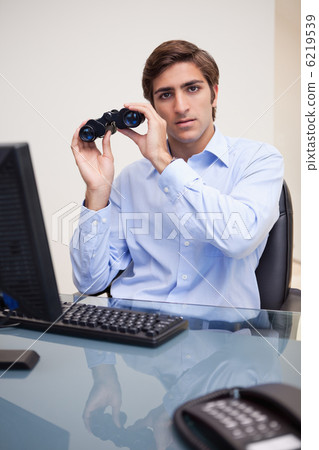 Businessman with binoculars in his office Businessman with binoculars in his office 6219539
