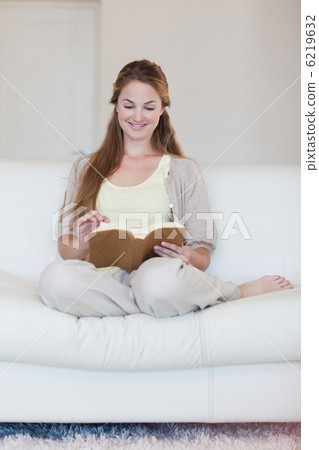 Woman enjoys reading a book on her sofa Woman enjoys reading a book on her sofa 6219632