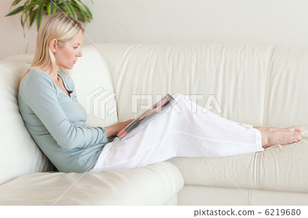 Side view of woman looking at catalog on the sofa Side view of woman looking at catalog on the sofa 6219680