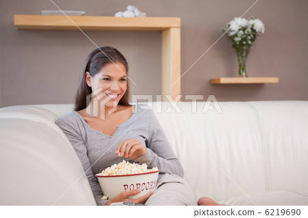 Smiling woman having popcorn while watching a movie 6219690