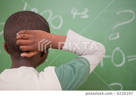 Schoolboy thinking with his hand on his head Schoolboy thinking with his hand on his head 6220197