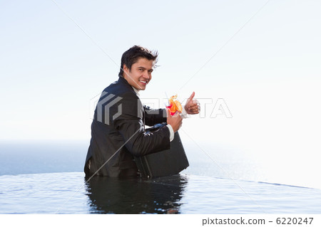 Portrait of a businessman posing with a cocktail and a briefcase 6220247