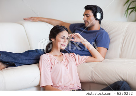 Woman watching TV while her husband is listening to music Woman watching TV while her husband is listening to music 6220252
